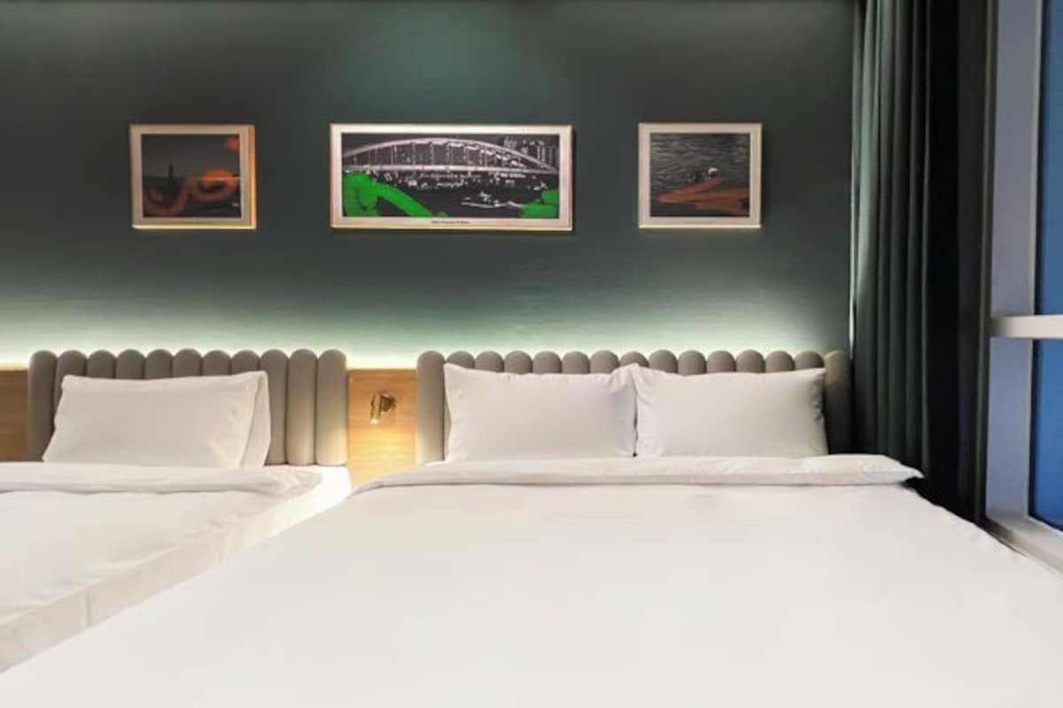 A hotel room with two beds, a headboard with a unique design, and three framed pictures on the wall.