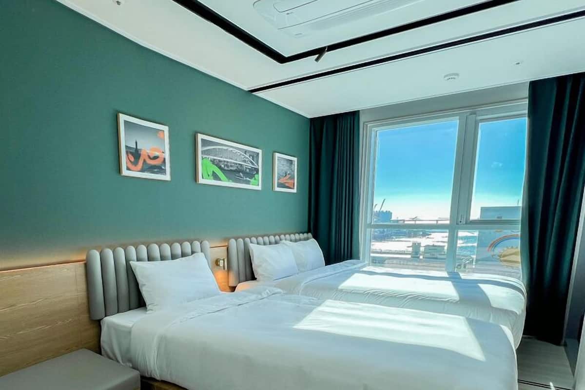 Un hotel moderno con una cama grande, vistas de la ciudad a través de amplias ventanas y obras de arte en la pared.