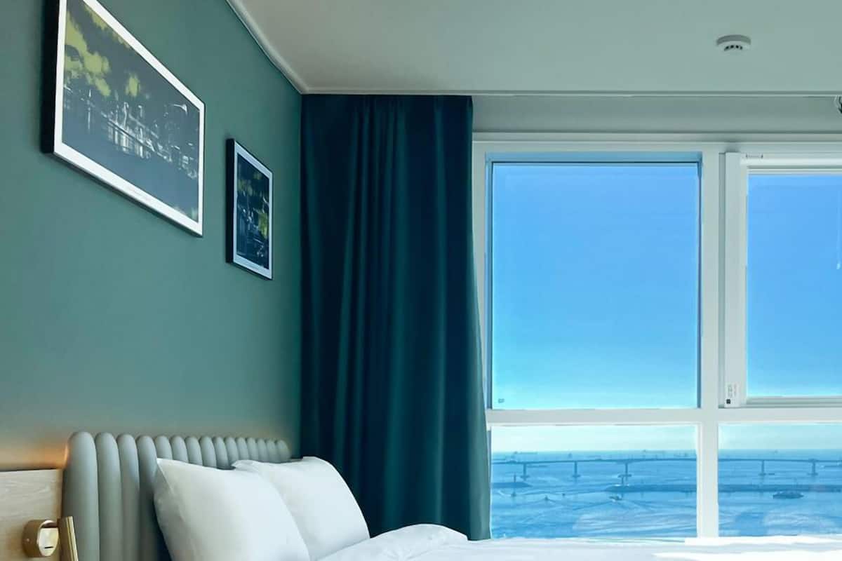 Habitación de hotel con una cama grande, vista al mar y dos cuadros en la pared.
