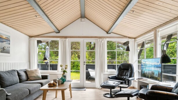 A spacious room with a high ceiling, large windows, a grey sofa, a coffee table, and a massage chair. - "Horsten" - 270m from the sea by Interhome (Nexø)