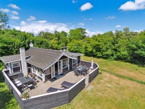 Enjoy outdoor gatherings on the large deck with seating and dining area surrounded by lush greenery.