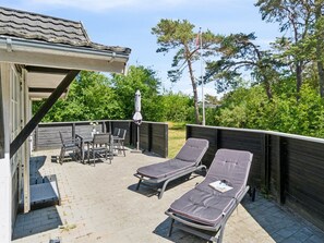 Relax on the outdoor patio with a wooden deck, table, and lounge chairs.