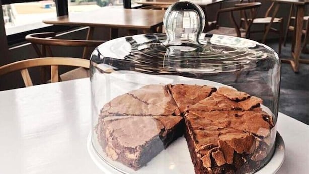 A dessert display with a glass dome cover on a white cake stand. - The Corner House (Kuala Belait)