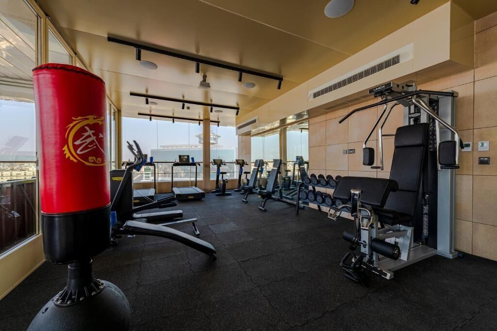 A modern gym with cardio equipment, weight machines, and a punching bag.