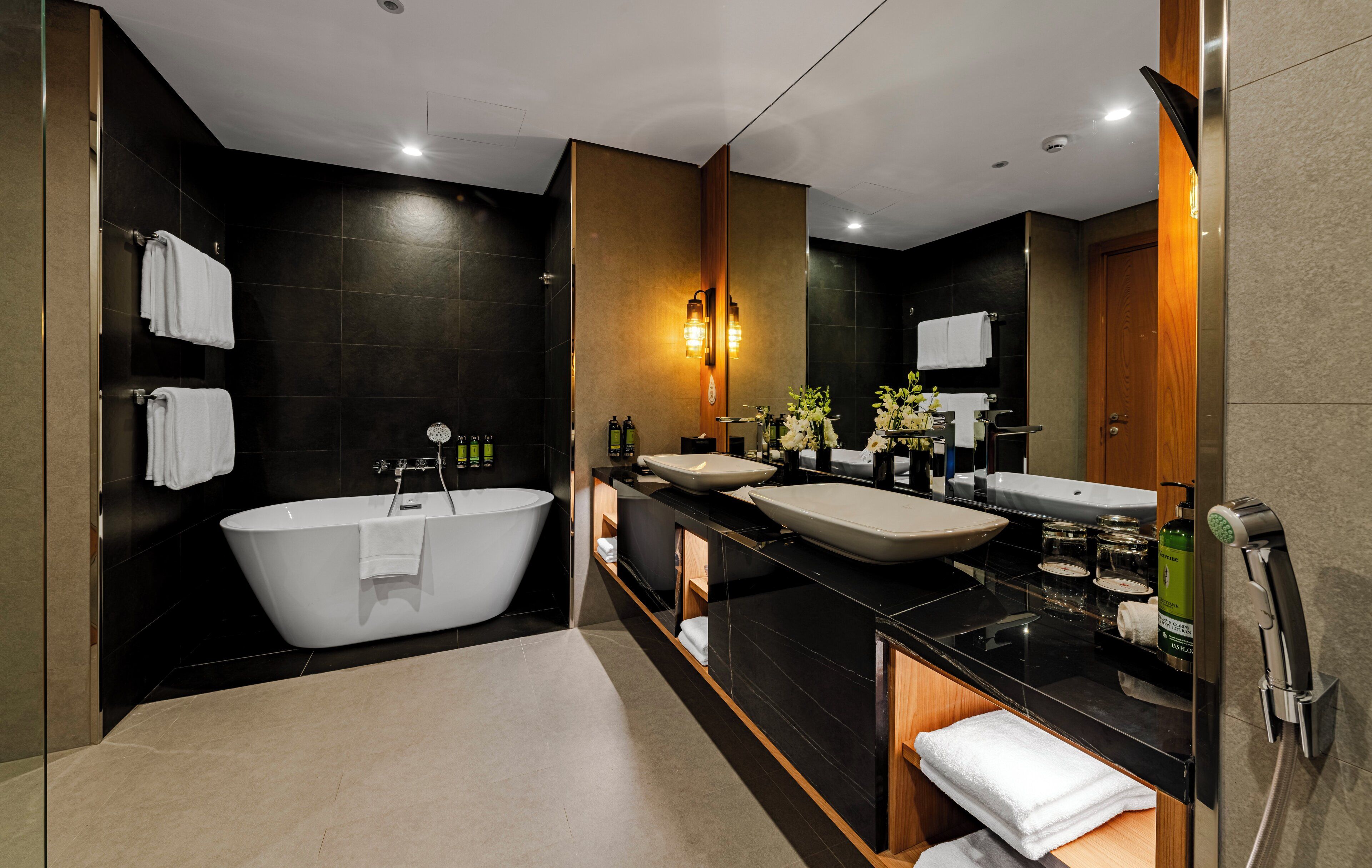 A modern bathroom with a freestanding bathtub, two sinks, and a large mirror.