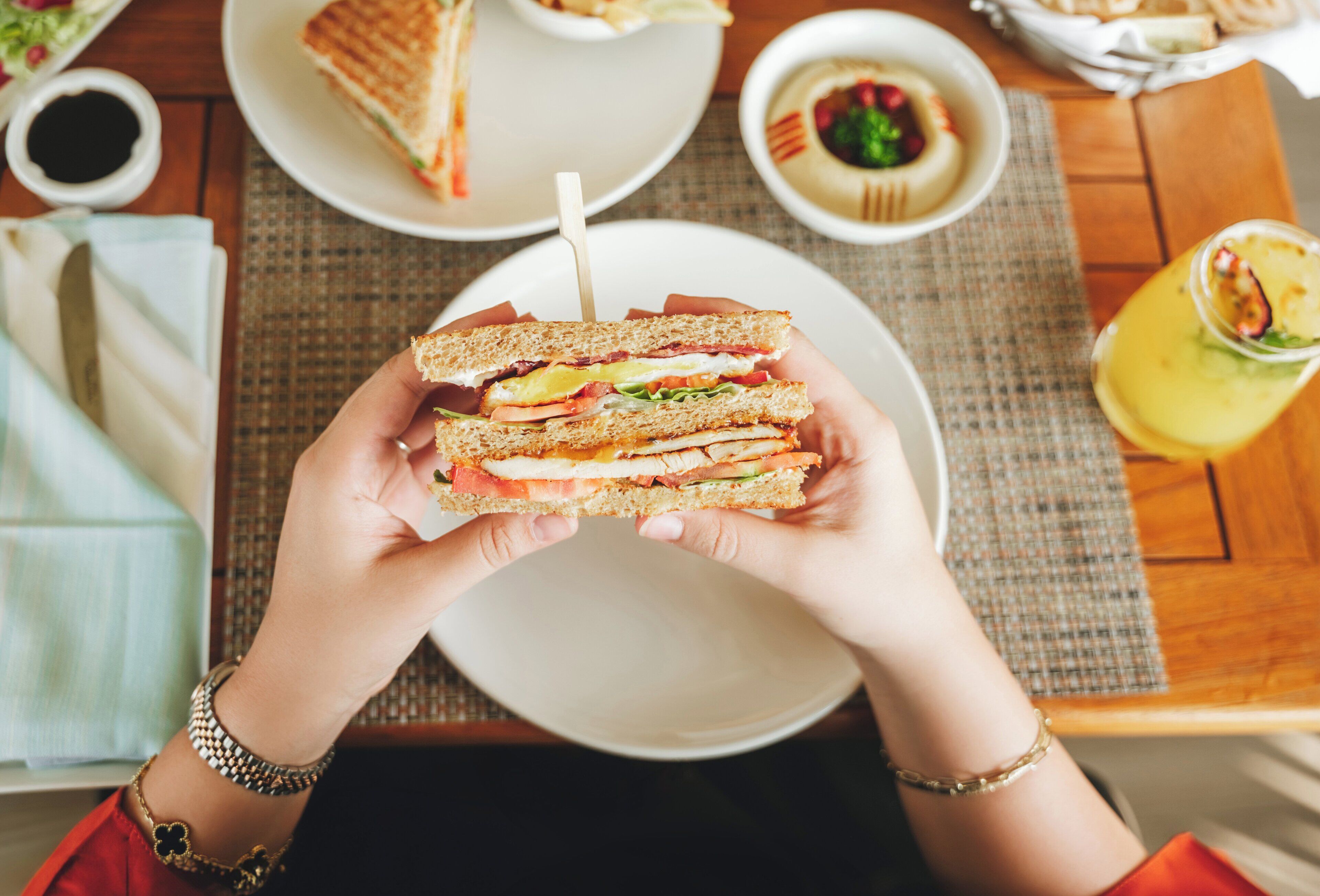 A person holding a sandwich with visible layers of ingredients.