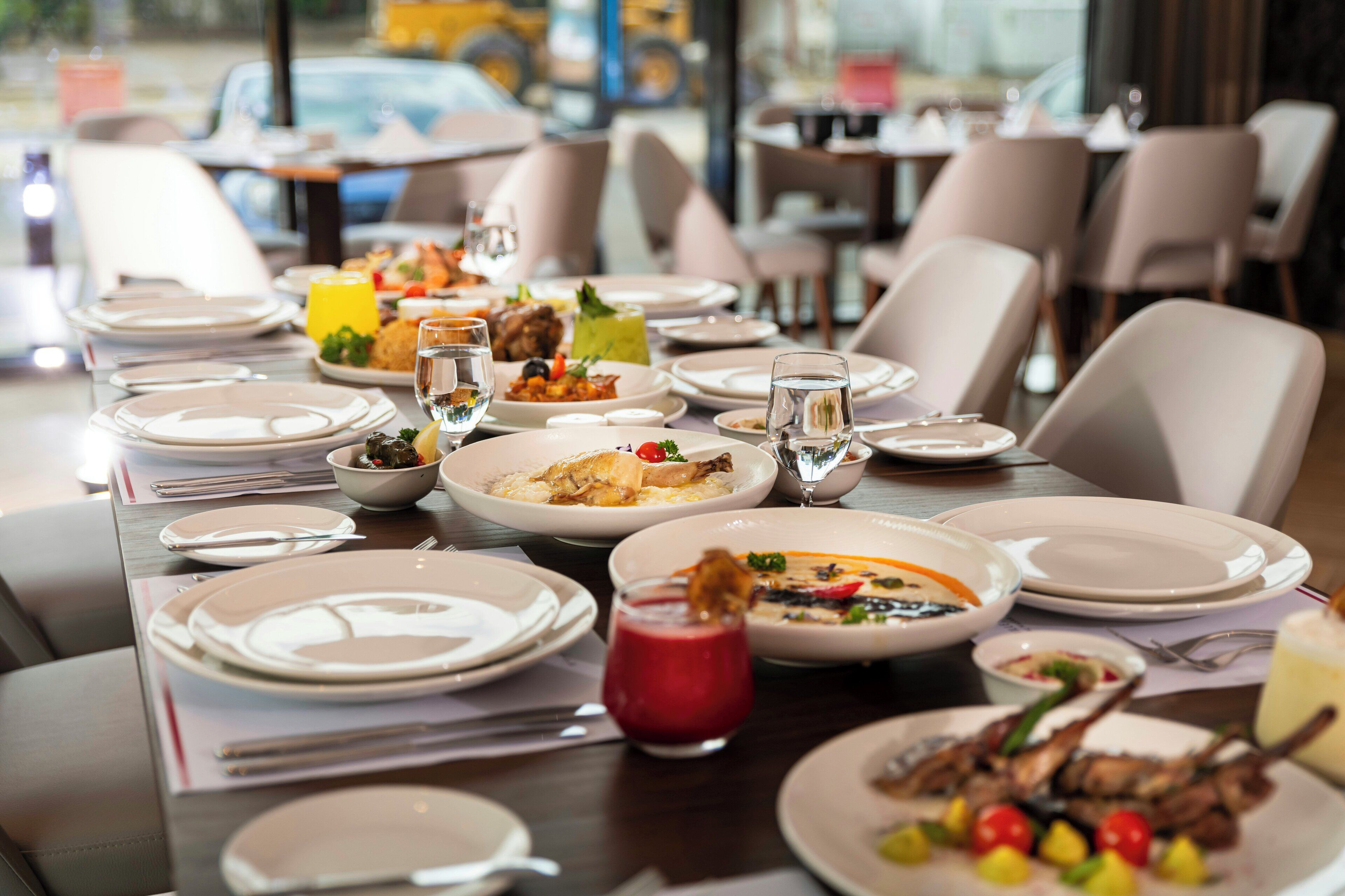 A restaurant table set with plates, glasses, and various dishes.