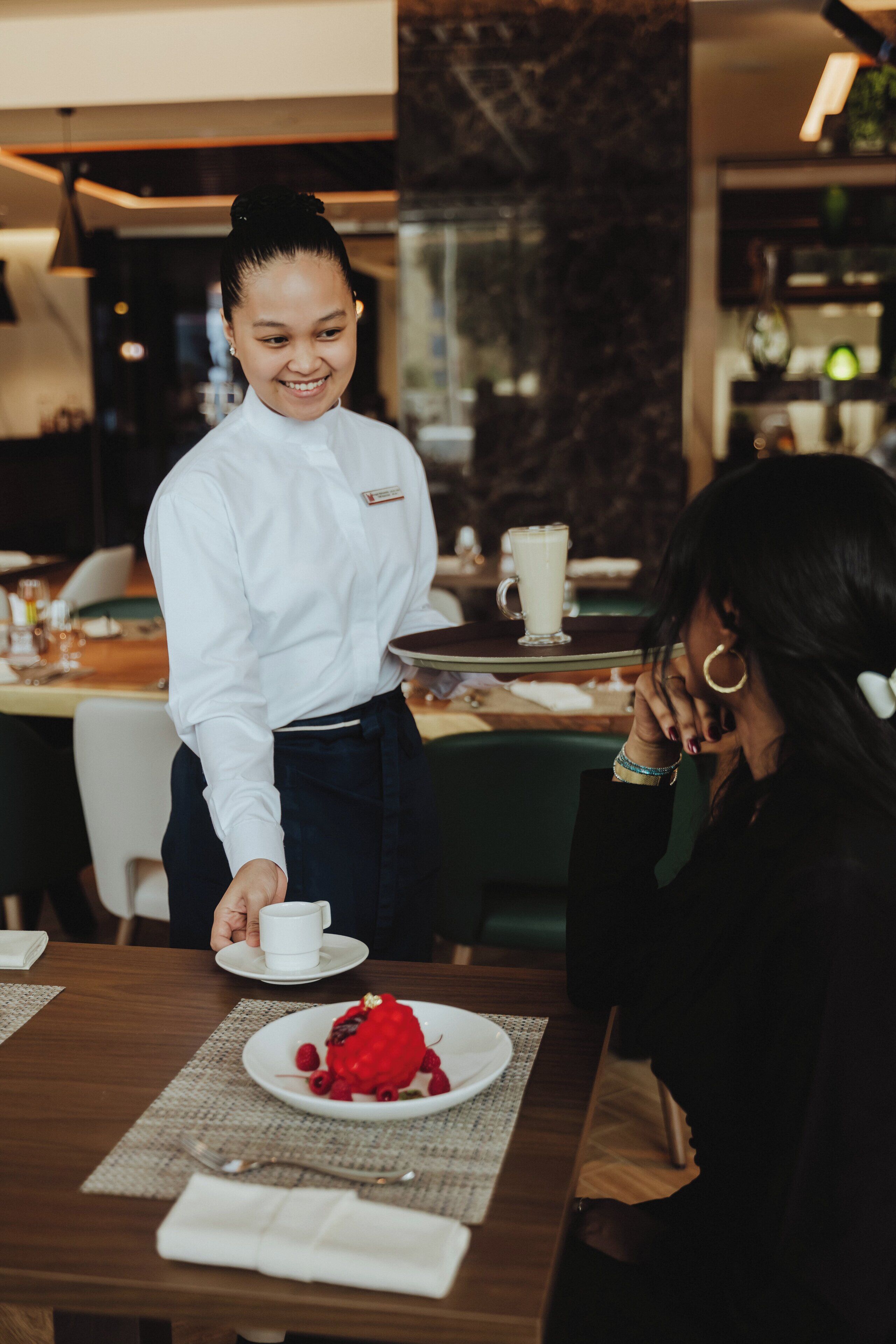 A restaurant setting with a waiter serving a meal to a customer.