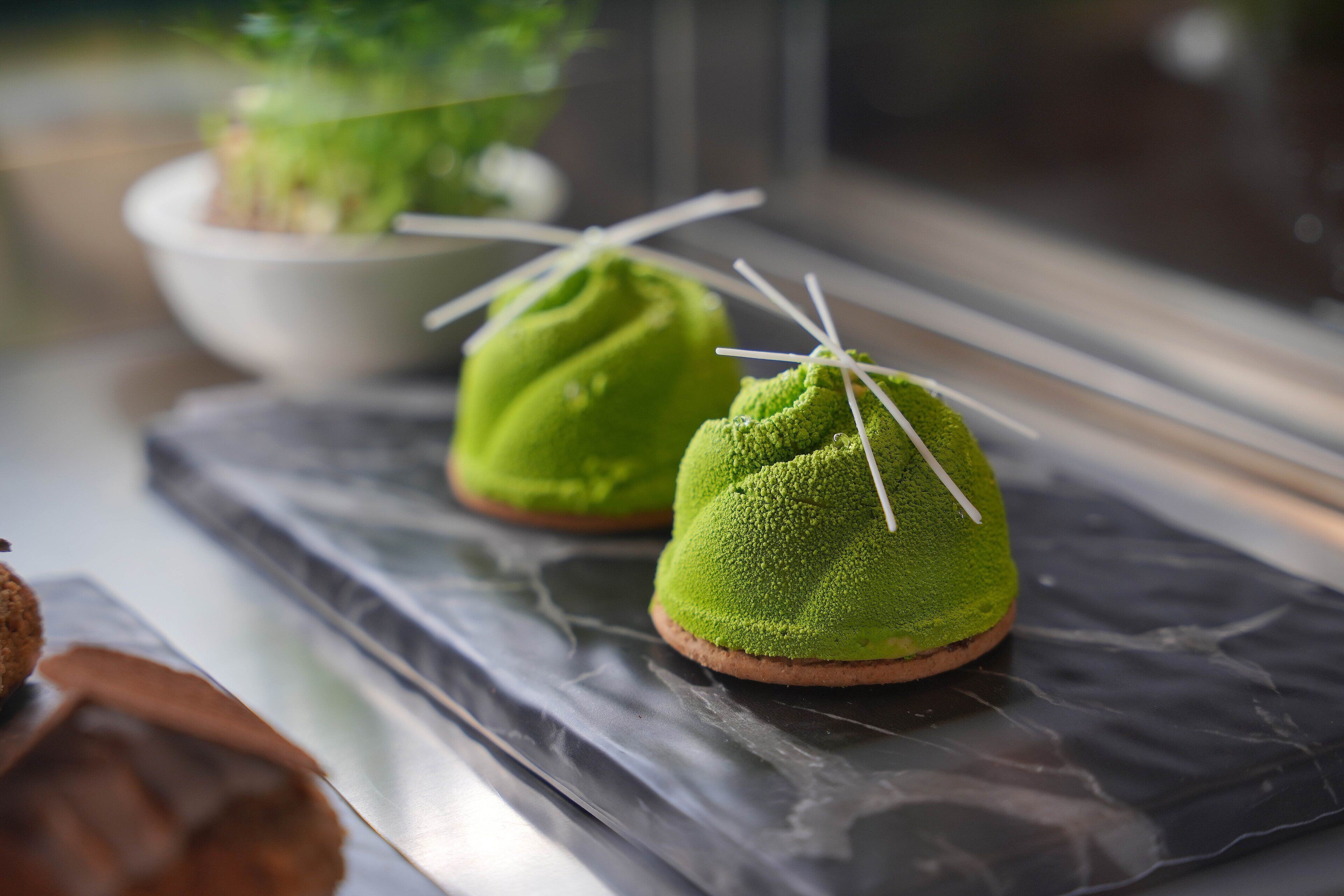 Two green desserts on a marble surface.