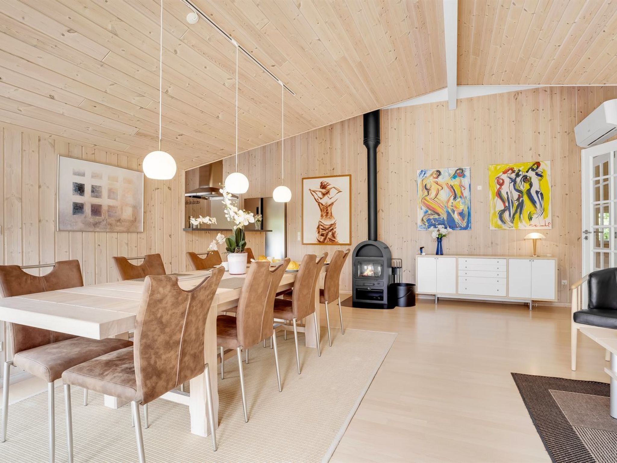 Un espace repas moderne avec un plafond en bois, une table centrale entourée de chaises et une cheminée.