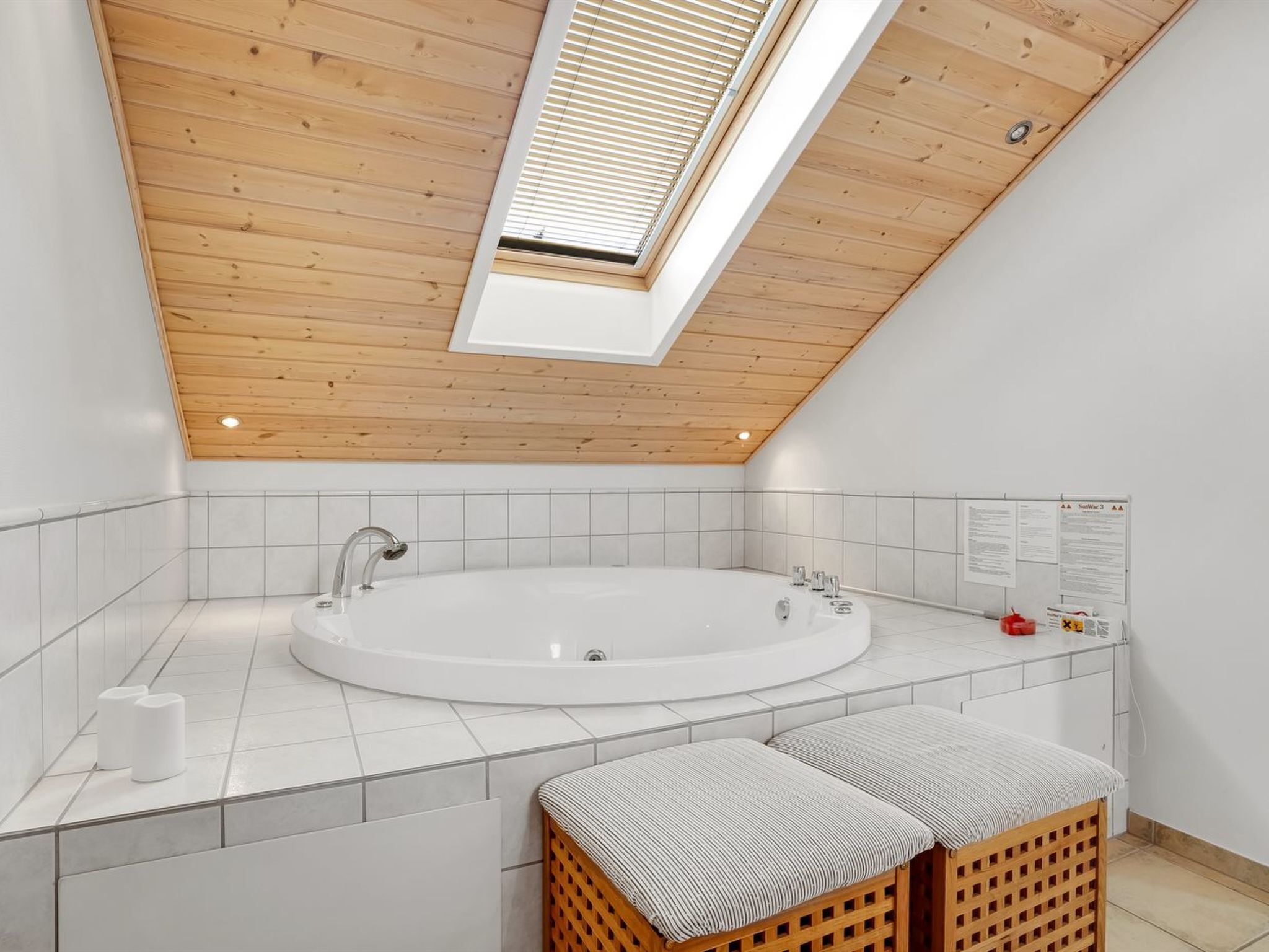 A modern bathroom with a freestanding bathtub, wooden ceiling, and a skylight.