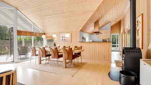 A modern kitchen with a wood-paneled ceiling, a central island, and a black stove.