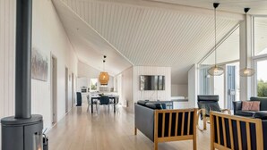 Un vaste espace de vie agrémenté d’une cheminée moderne, d’une table à manger et de sièges confortables.