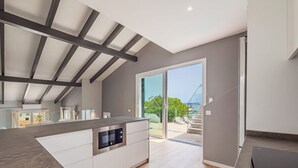 Eine moderne Küche mit einer großen Kochinsel, integrierten Geräten und einer Glastür, die auf einen Balkon führt.