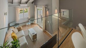 Ein modernes Wohnzimmer mit einer Couch, einem kleinen Tisch und einem Glasgeländer mit Blick auf einen Balkon.