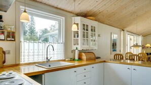 Una cocina con armarios de madera, un lavabo y un ventanal con vistas a árboles.
