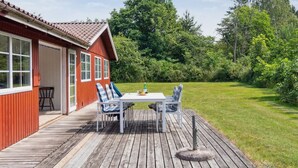A wooden deck with a table and chairs, a red building with white trim, and a grassy yard with trees. - "Fritza" - 500m from the sea by Interhome (Fårevejle)