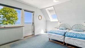 Une chambre avec une grande fenêtre, un puits de lumière et une vue sur la mer.