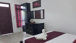 Une chambre d’hôtel avec un lit, une armoire, un miroir et une porte.