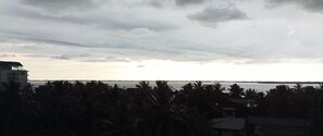 Vista costera con un edificio a la izquierda y una masa de agua al fondo.