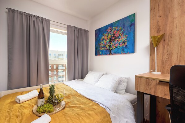 A hotel room with a bed, a desk, a chair, a painting, and a window with curtains. - Lumina apart near Muzeum Włókiennictwa (Lodz)