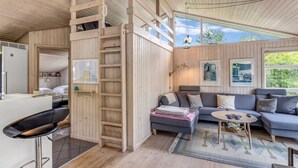 A cozy cabin interior with a loft bed, a sofa, a coffee table, and a dining area. - "Anouk" - 2km from the sea by Interhome (Saltum)