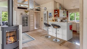A modern kitchen with a central island, bar stools, a built-in stove, and wooden cabinetry. - "Anouk" - 2km from the sea by Interhome (Saltum)