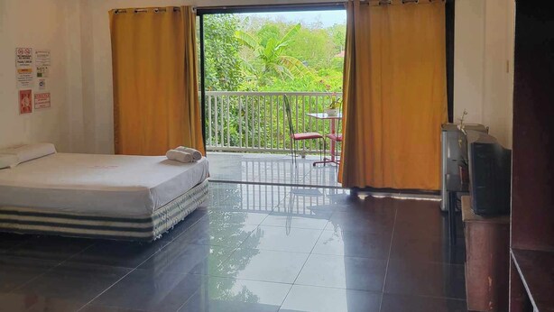 A hotel room with a bed, a TV, and a balcony with curtains. - Wjv Inn Marigondon (Lapu-Lapu)