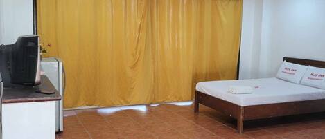 Una habitación con una cama, un escritorio y una cortina amarilla.