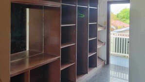 A hallway with a wooden shelving unit, a tiled floor, and a view of a balcony with a railing. - Wjv Inn Marigondon (Lapu-Lapu)