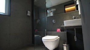 Ein modernes Badezimmer mit Duschkabine aus Glas, einer weißen Toilette und einem Waschbecken mit Spiegel darüber.