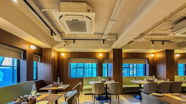 Ein Restaurant mit Sitzboxen und Tischen, Holzvertäfelung und großen Fenstern.