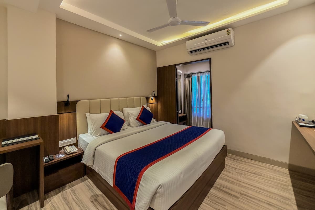 Una camera d'albergo con un letto, un comodino, una scrivania e un condizionatore d'aria.