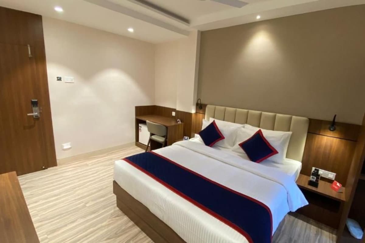 A hotel room with a large bed, a desk, and a wardrobe.