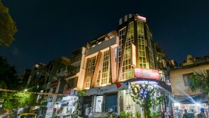 A multi-story building with a J&K Bank sign, a holiday home sign, and a Coca-Cola sign. - Hotel Batra Holiday Home (New Delhi)