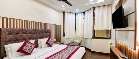 Une chambre d’hôtel moderne avec un grand lit, un ventilateur de plafond, une télévision et une fenêtre avec des rideaux.