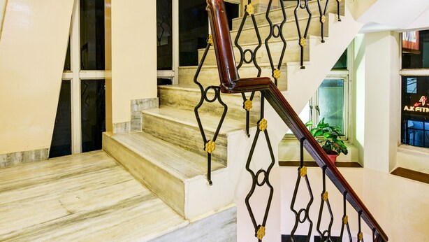 A marble staircase with a geometric metal railing and a potted plant at the top. - Hotel Batra Holiday Home (New Delhi)