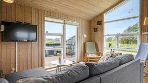 A modern living room with a large grey sofa, a television mounted on the wall, and a wooden ceiling. - "Niesina" - 200m from the sea by Interhome (Løkken)