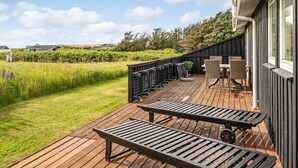 A wooden deck with outdoor furniture, a view of the countryside, and a building with large windows. - "Niesina" - 200m from the sea by Interhome (Løkken)