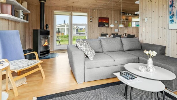 A cozy living room with a fireplace, a grey sofa, a round coffee table, and wooden flooring. - "Niesina" - 200m from the sea by Interhome (Løkken)