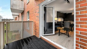 A modern apartment with a balcony, a sliding glass door leading to a living area, and a brick exterior.