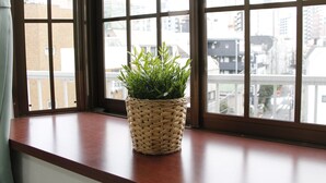 Une fenêtre avec un panier tressé contenant des plantes vertes, posé sur un rebord en bois.