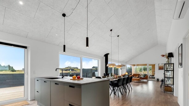 A spacious kitchen with a large island, modern pendant lights, and a view of the outdoors.
