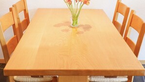 A wooden dining table with a vase of flowers in the center, surrounded by four chairs. - Haus Judith - Bonita by Interhome (Saas-Fee)