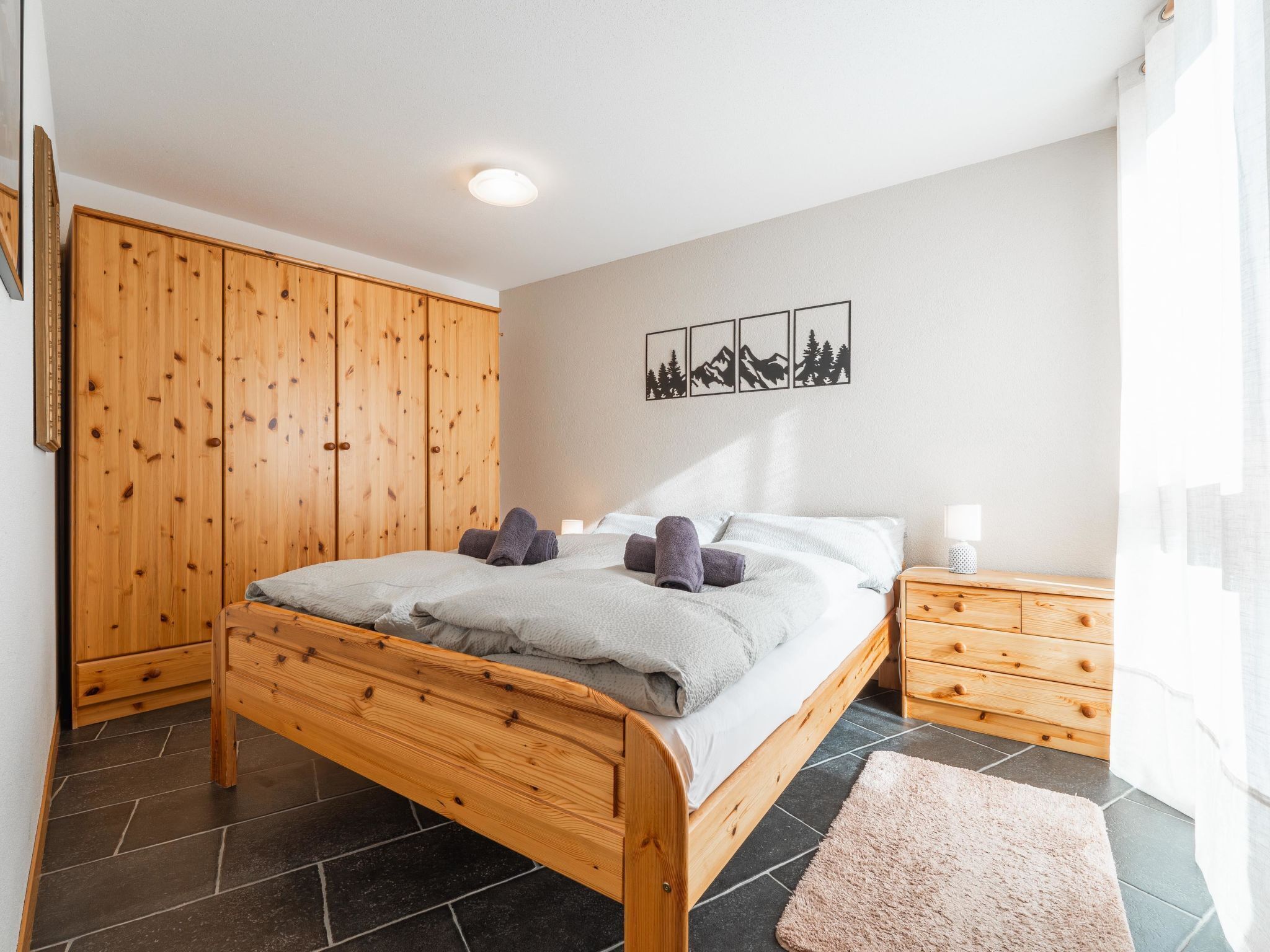 Une chambre à coucher avec un lit en bois, une armoire, une table de chevet et un tapis.