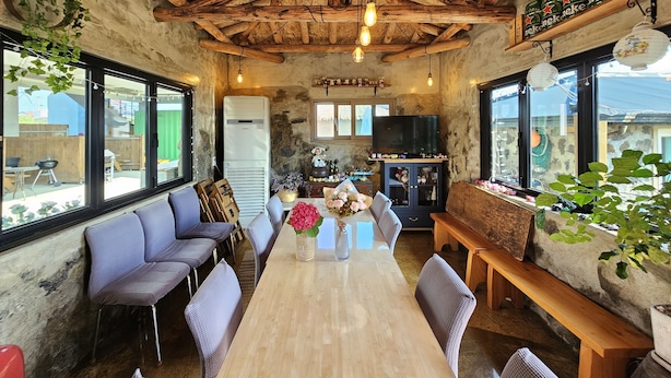 Un interior rústico con vigas de madera a la vista, una larga mesa de comedor de madera y un mobiliario cómodo.