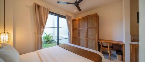 A bedroom with a bed, a desk, a chair, a ceiling fan, and a window with curtains.