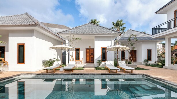 A modern resort with a swimming pool, sun loungers, and a covered patio area. - Lala Panzi Villa (Jimbaran)