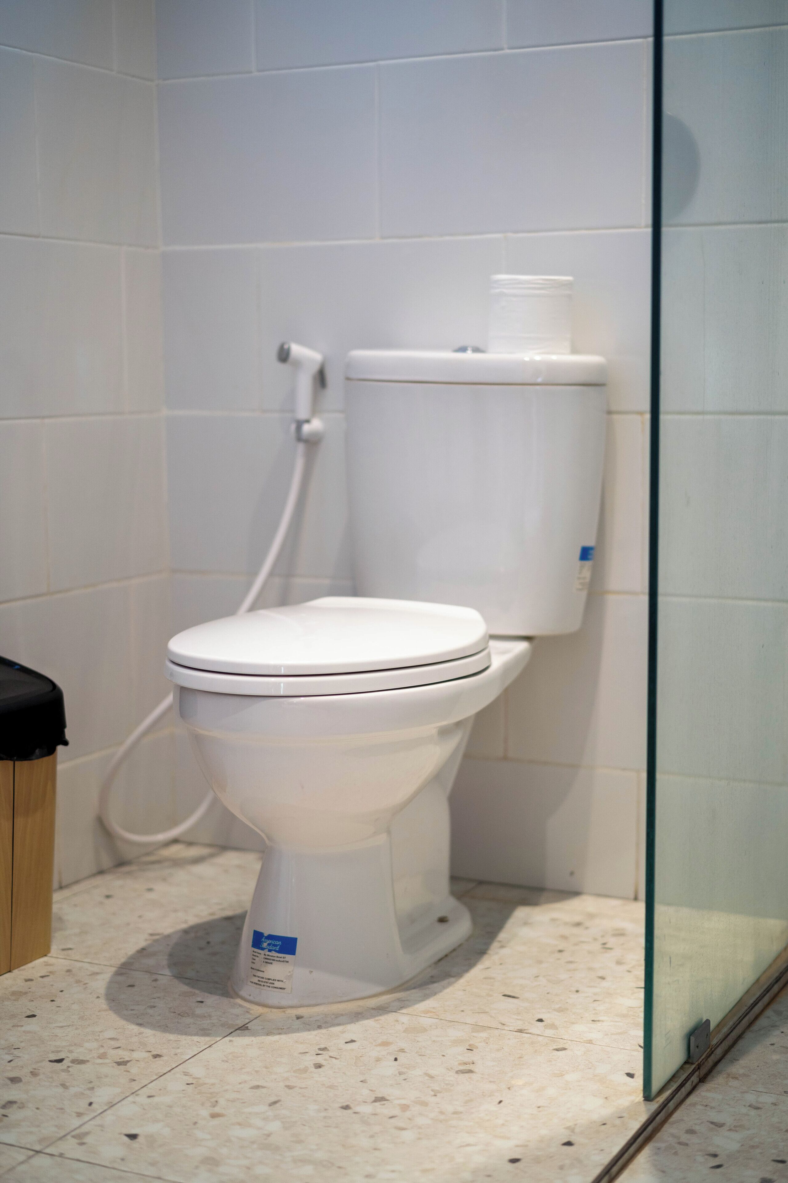 A white toilet in a bathroom with a tiled floor and a glass shower door.
