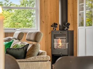 Una habitación acogedora con sofá, chimenea y ventana con vistas a árboles.